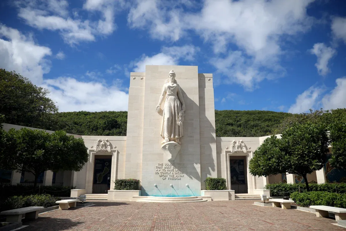 The Honolulu Memorial's Lady Columbia statue and brick court at the National Memorial Cemetery of the Pacific (Punchbowl), green crater slope behind, a stop on Pearl Harbor tours from Honolulu